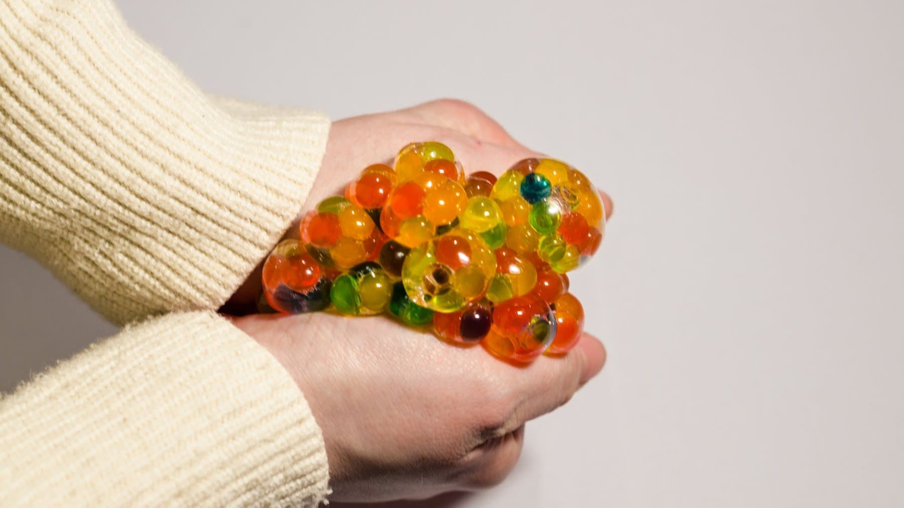 une femme qui tient des orbeez entre les mains et qui appliquent une pression sur ces orbeez pour évacuer le stress