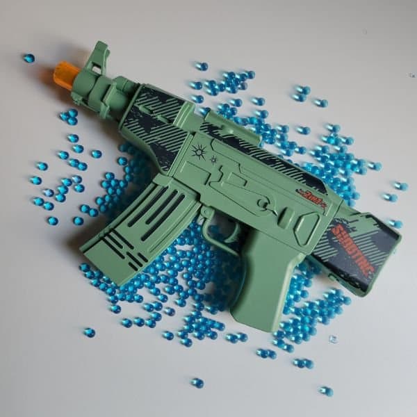 pistolet à orbeez ak47 Élite pour enfant de couleur verte avec des balles d'orbeez sur la surface