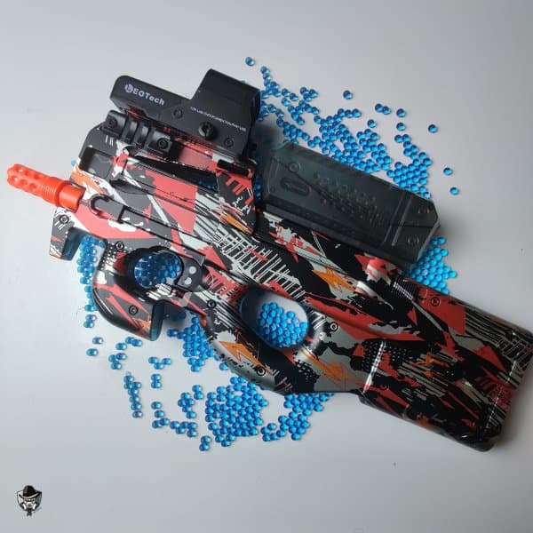 P90 gel blaster de couleur rouge graffiti avec tous ses accessoires sur un fond blanc et des orbeez bleu