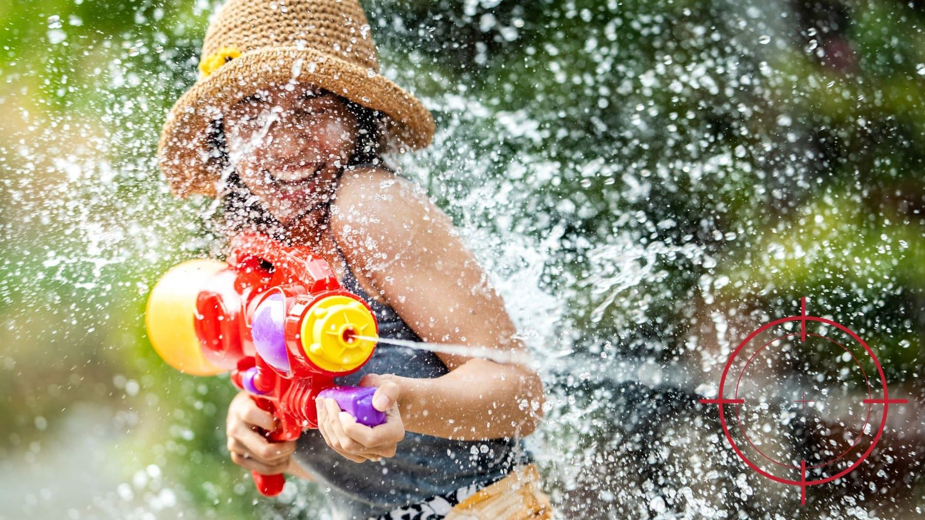 Une fille avec un pistolet à eau qui joue dans un jardin